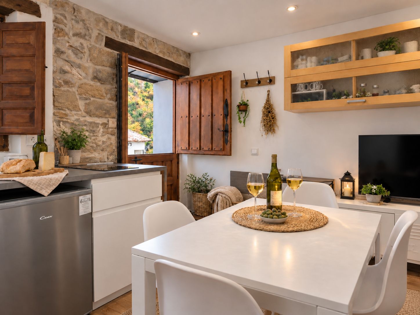 Cocina moderna con paredes de piedra, armarios de madera y un comedor con mesa para dos.