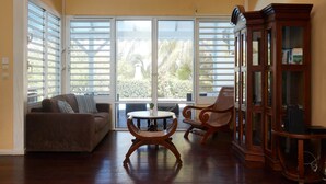 Un salon avec un canapé, une table ronde et deux fauteuils en osier.