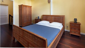 Ein Schlafzimmer mit einem hölzernen Bett, einem Nachttisch, einem Kleiderschrank und einer Lampe.