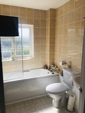A bathroom with a bathtub, toilet, and sink. - Delightful seaside cottage, central, quiet with free parking. Sleeps 5. (Deal)