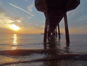 A pier extending into the water with the sun setting in the background. - Delightful seaside cottage, central, quiet with free parking. Sleeps 5. (Deal)