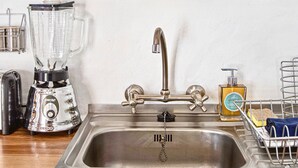 Eine Küche mit einem Edelstahl-Spülbecken, einem Mixer, einer Kaffeemaschine und verschiedenen Küchengeräten.