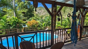 A wooden deck with a pool, surrounded by lush greenery and a mountainous backdrop. - Maison Forban - Villa Ti-Polo (Deshaies)