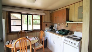 Une cuisine compacte avec des meubles de rangement en bois, une cuisinière et un coin repas avec des chaises.