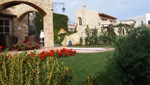 A stone building with a garden, a fountain, and a flag.