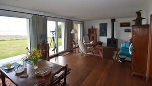Uma sala de estar espaçosa com área de jantar, grandes janelas e vista para o exterior.