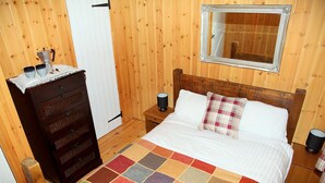 A wooden room with a bed, a dresser, a mirror, and a colorful quilt. - Silver Birch Cabin - Charming Log Cabin with bags of character and hot tub. (Dalavich, Taynuilt)