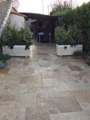 A paved courtyard with two planters on either side, a covered seating area, and a staircase leading to a building. - house with pool in beausset (Le Beausset)