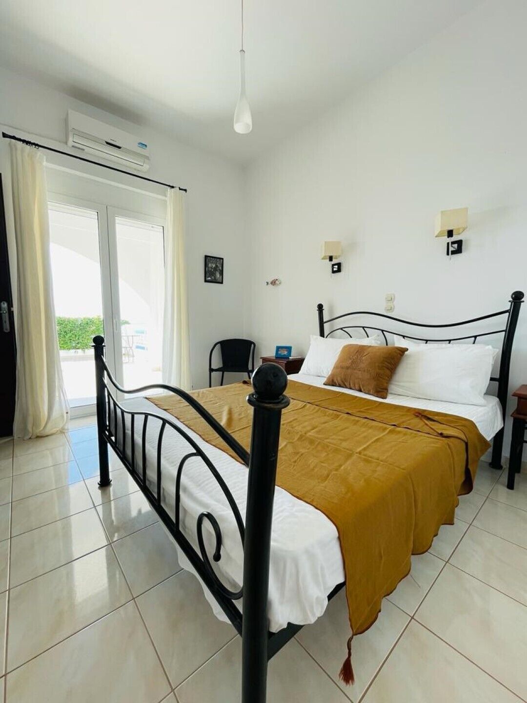 Een slaapkamer met een bed, een stoel, een bureau en een airconditioning.