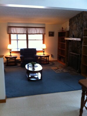 Relax in this inviting living room with a fireplace, comfortable armchair, and coffee table.