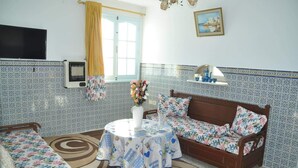 A cozy living room with a sofa, a table with a floral tablecloth, a TV, and patterned walls. - City Apartment on the port of Mahdia Free Wifi (Mahdia)