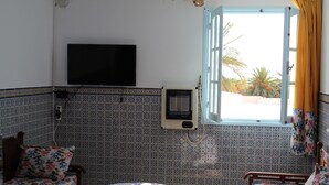 A room with a bed, a small round table, a TV mounted on the wall, and a window with curtains. - City Apartment on the port of Mahdia Free Wifi (Mahdia)