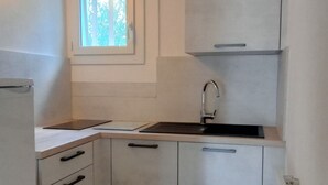 A compact kitchen with a window, a sink, and cabinets. - Vacation (SAINT REMY DE PROVENCE)
