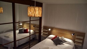Ein Hotelzimmer mit zwei Betten, Holzkopfteilen und einem großen Spiegel.
