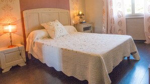 A bedroom with a large bed, a nightstand with a lamp, and a window with curtains. - House 7 persons  with large pool in corbieres area (Talairan)