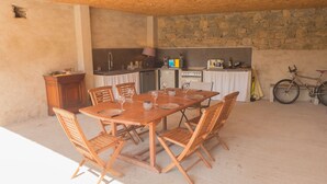 A rustic dining area with a wooden table and chairs, a stone wall, and a bicycle. - House 7 persons  with large pool in corbieres area (Talairan)