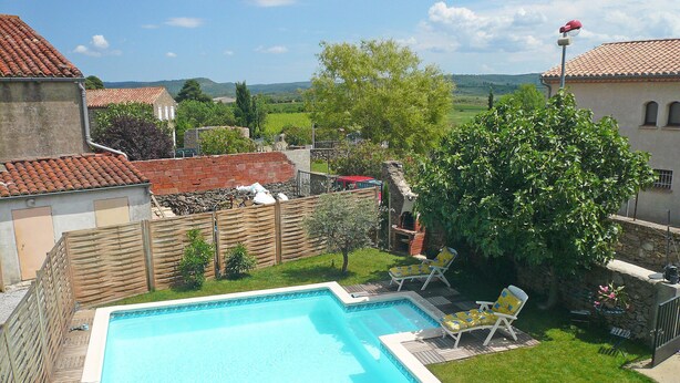 A swimming pool with a wooden deck and lounge chairs, surrounded by a stone wall and greenery. - House 7 persons  with large pool in corbieres area (Talairan)