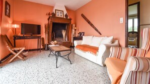 A living room with a fireplace, a television, a sofa, and a striped armchair. - House 7 persons  with large pool in corbieres area (Talairan)