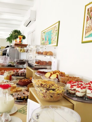 A buffet with various food items and a plant on the wall.