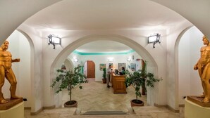 Hotellin aula, jossa on korkea katto, holvikatto ja vastaanottotiski.
