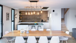Een moderne keuken met een houten eiland, hanglampen en een klok aan de muur.