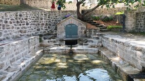 A stone well with a green door, surrounded by stone walls and steps leading up to a stone staircase. - Villa O Bord de l'O Sainte Marine, sea view, swimming pool 29°, beach access (Combrit)