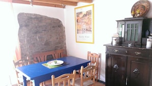 A dining area with a blue table, wooden chairs, a stone wall, and a cabinet with a green glass door. - Curr. M.Flair, quiet location, grGarten, fenced.2km, directly to the forest / meadow, gr. Lake (Blankenheim-Reetz)