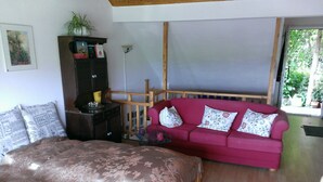 A bedroom with a large bed, a red sofa, and a wooden cabinet. - Curr. M.Flair, quiet location, grGarten, fenced.2km, directly to the forest / meadow, gr. Lake (Blankenheim-Reetz)
