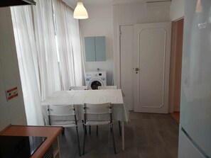 A small kitchen with a table and chairs, a washing machine, and a door.