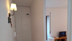 A hallway with a white door, a wall-mounted lamp, and a welcome sign. - Sweet Garden Cascais - Checkinhome (Cascais)