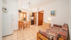 Ein gemütlicher Raum mit Bett, Esstisch und Stühlen, einer Küchenzeile und einem kleinen Badezimmer.