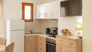 Eine kleine Küche mit Kühlschrank, Herd, Spüle und Holzschränken.