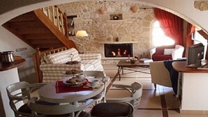 Ein gemütliches Wohnzimmer mit Kamin aus Stein, einem Essbereich mit Tisch und Stühlen sowie einer Treppe zu einer oberen Ebene.
