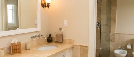 A bathroom with two sinks, a large mirror, and a shower area.