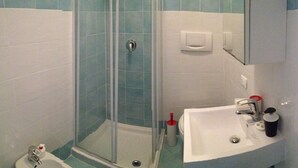 A bathroom with a glass shower enclosure, a sink, and a toilet.