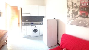 A compact living space with a television, a wooden bench, a washing machine, and a refrigerator.