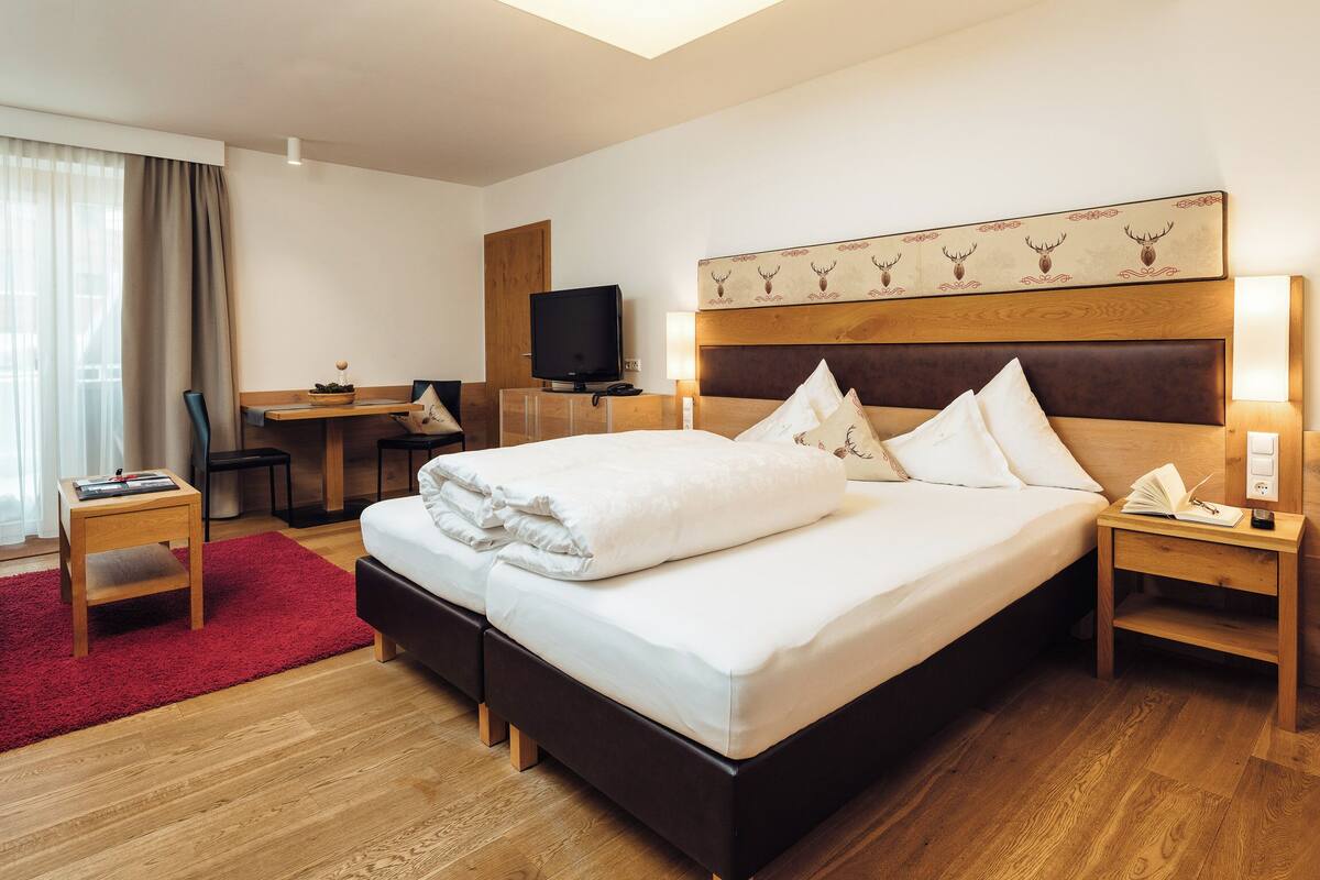 Ein Hotelzimmer mit einem großen Bett, einem Schreibtisch mit Fernseher und einem roten Teppich.