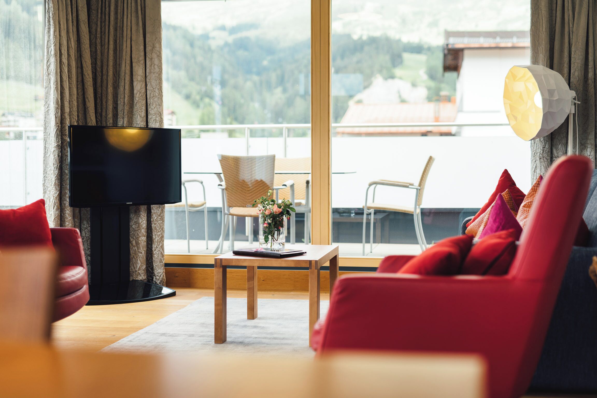 Un salon moderne avec un téléviseur, une table basse en bois et des canapés rouges.