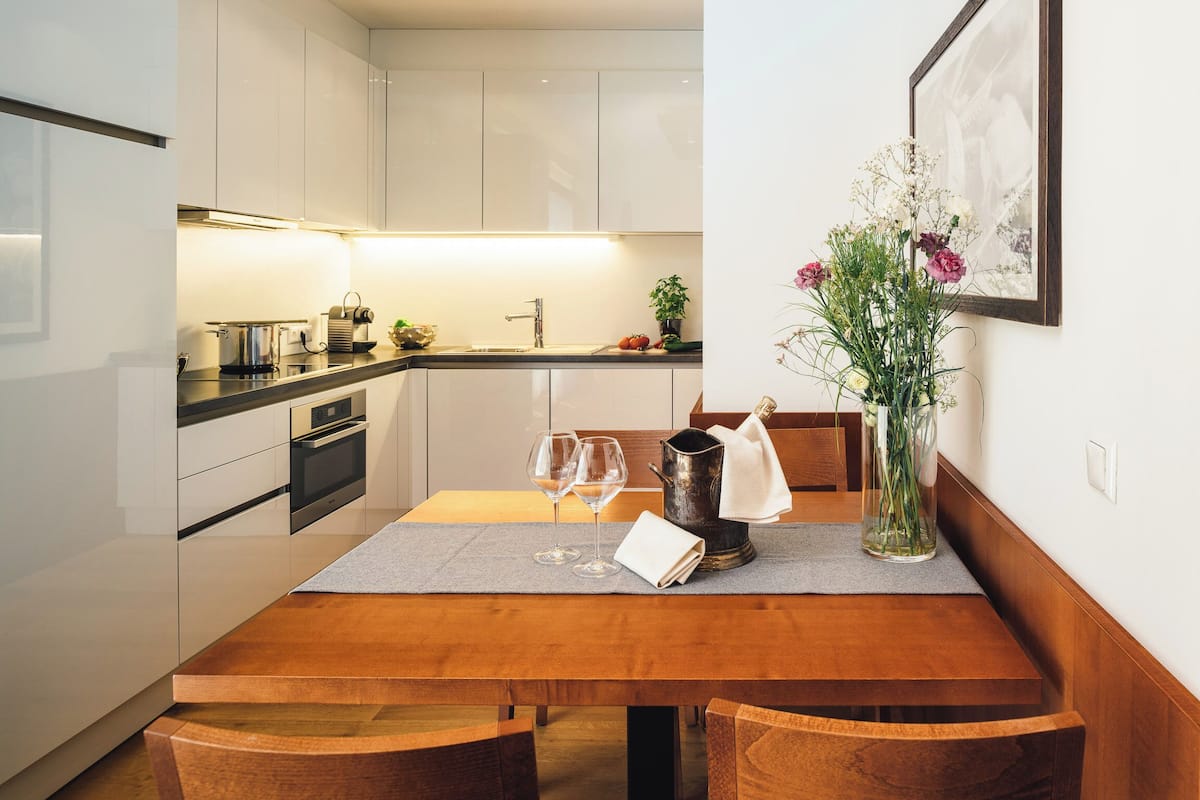 Eine moderne Küche mit weißen Schränken, einem Holzespeisetisch und einer Vase mit Blumen.