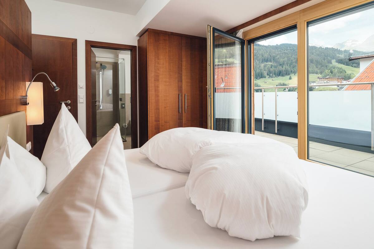 Ein Hotelzimmer mit einem großen Bett, einer Dusche und einem Balkon mit Blick auf die Landschaft.