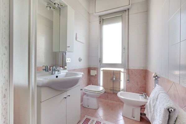A bathroom with a sink, toilet, bidet, and a large mirror.
