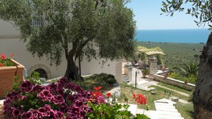 A terrace with a view of the sea, surrounded by potted plants and a stone bench. -   XIXth century VILLA BASSO in Gargano- holiday rental overlooking the sea (Mont Sant'Angelo)