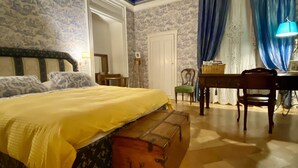 A bedroom with a bed, a wooden chest, a desk, and a chair. -   XIXth century VILLA BASSO in Gargano- holiday rental overlooking the sea (Mont Sant'Angelo)
