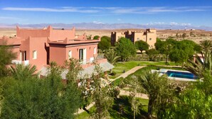 Un resort en el desierto con arquitectura tradicional, una piscina y vistas a montañas distantes.