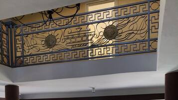 Une pièce spacieuse avec un plafond décoré, un coin repas comprenant une table et des chaises, et une vue sur l’extérieur grâce à une grande fenêtre.