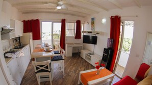 Een compacte, goed verlichte kamer met een kitchenette, een eethoek en zithoek.