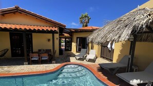 A swimming pool with a tiled edge, surrounded by lounge chairs and a table with chairs. - Aruba Villa with Pool, just 3 minutes driving from Aruba's best beaches (Noord)