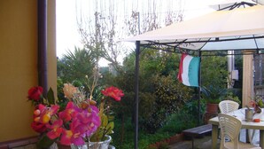 Eine Terrassengruppe im Freien mit Tisch, Stühlen, einer Blumenvase und einer Flagge.