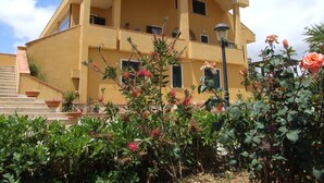 A multi-story building with balconies and a garden area with flowers. - B & B St. ELIA suite ROSA: CHARMING VILLA IMMERSED IN THE HISTORIC PARK DUBINI (caltanissetta)