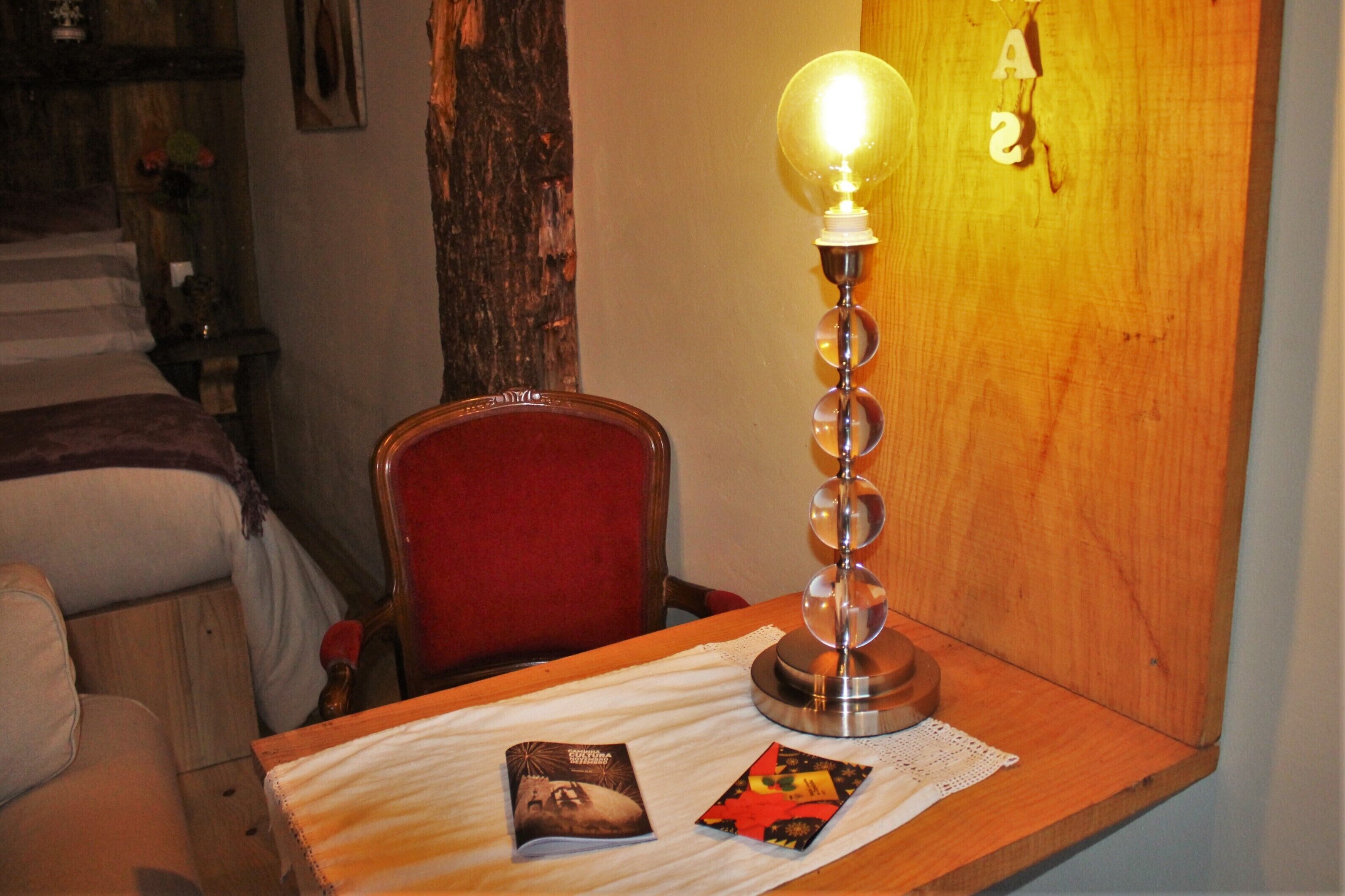A wooden table with a lamp, a chair, and two pamphlets.